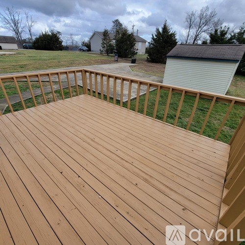 A wooden deck with a railing and a grassy area in the background.