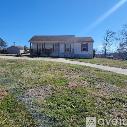 A small house with a porch is situated in a grassy area.