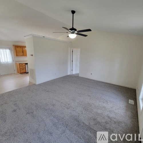 A spacious room with a ceiling fan and carpeted floor.