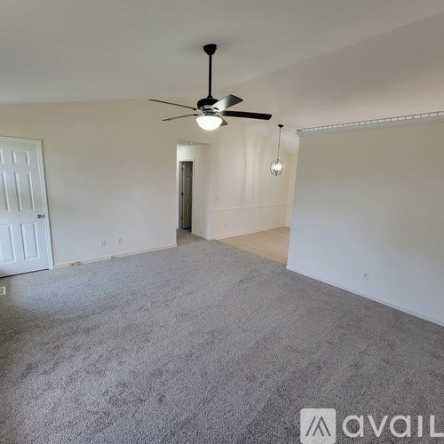 A room with a ceiling fan and carpeted floor.