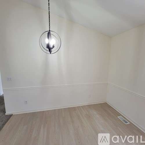 A room with a wooden floor and a hanging light fixture.