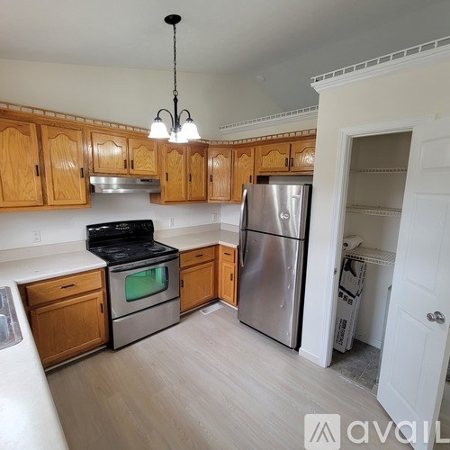 A kitchen with wooden cabinets and a stainless steel refrigerator.