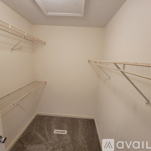 A small, empty room with a carpeted floor and three metal shelves.