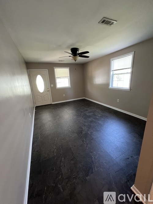 A room with a ceiling fan and two windows.