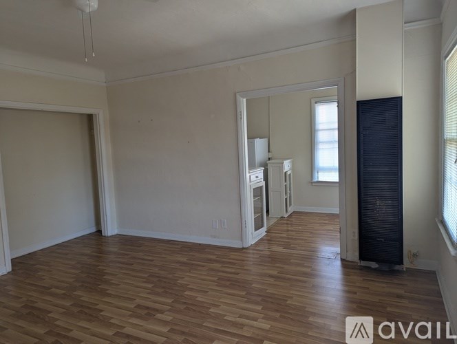 A room with wooden flooring and a window with blinds.