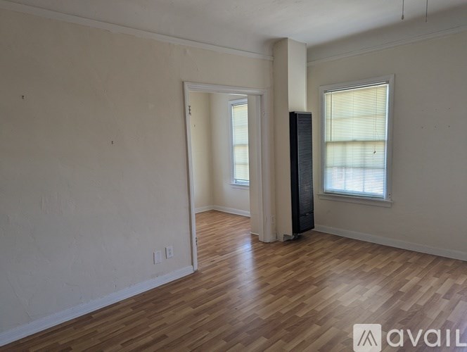 A room with wooden flooring and a window with blinds.