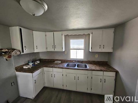 A kitchen with white cabinets and a brown countertop.
