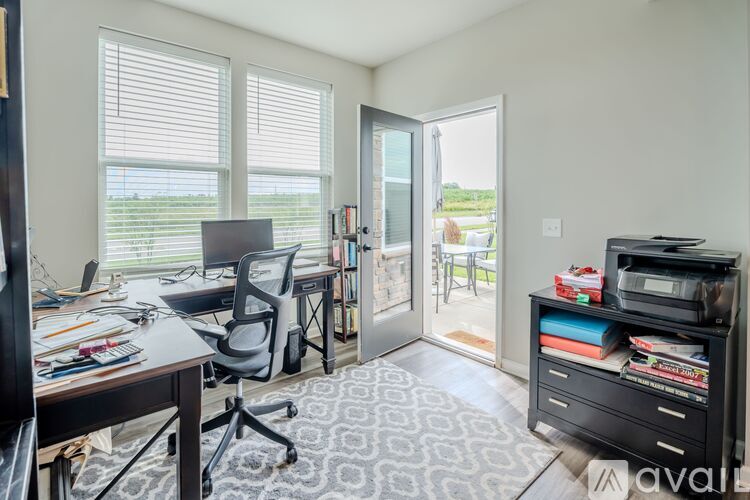A room with a desk, chair, and a printer on a cabinet.