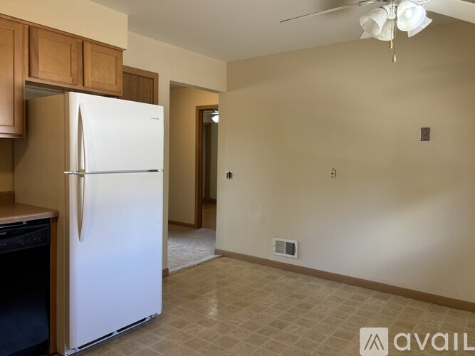 A kitchen with a white refrigerator and wooden cabinets.