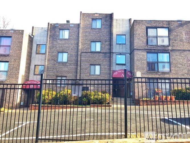 A brick building with a black fence in front.