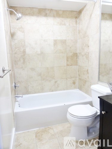 A white toilet sits next to a bathtub in a bathroom.