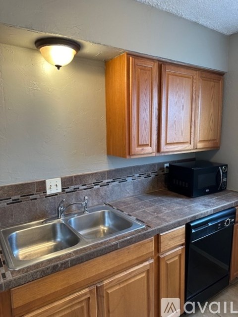 A kitchen with wooden cabinets and a black toaster oven on the counter.