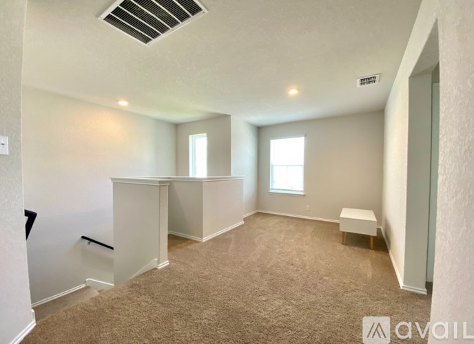 A spacious room with carpeted floor and two windows.