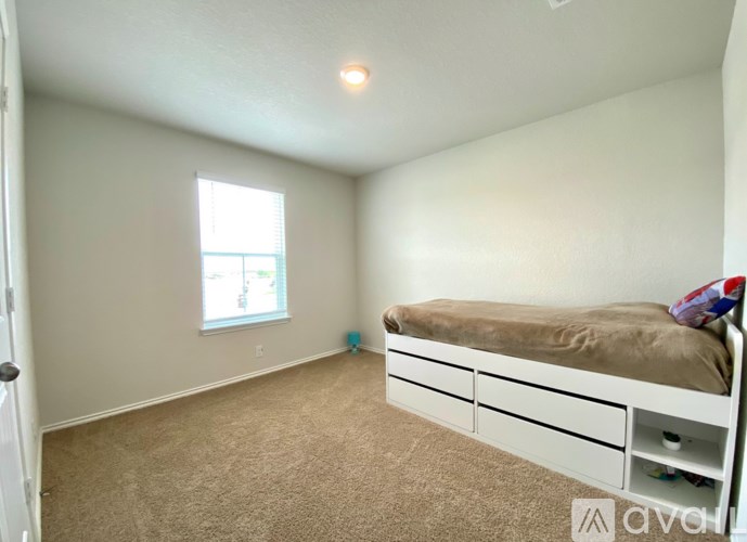 A bedroom with a bed, carpet, and a window.