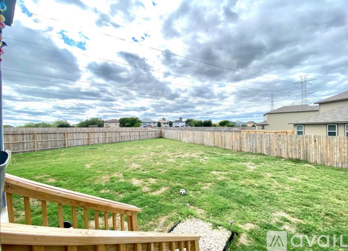 A backyard with a wooden fence and a soccer ball in the grass.