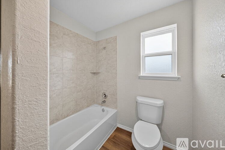 A bathroom with a toilet, tub, and window.