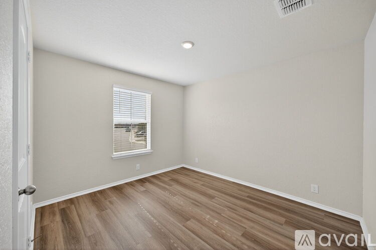 A room with wooden flooring and a window with blinds.