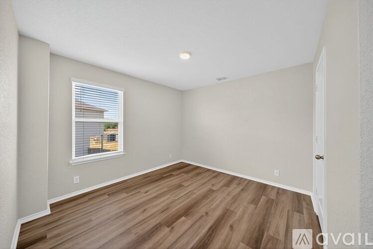 A room with wooden flooring and a window with blinds.