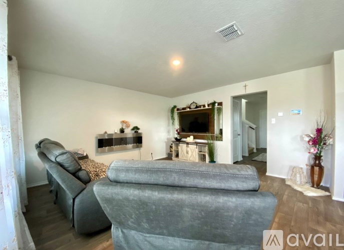 A living room with a grey sofa and a fireplace with a mantlepiece above it.