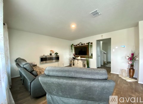 A living room with a grey sofa and a fireplace with a mantlepiece above it.
