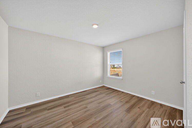 A room with wooden flooring and a window with blinds.
