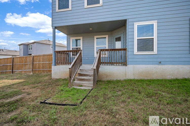 A blue house with a wooden fence and a staircase leading to the front door.