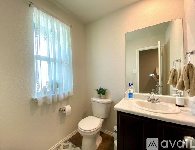 A bathroom with a toilet, sink, and mirror.