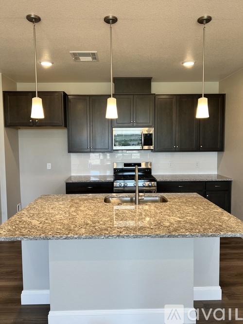 A kitchen with granite countertops and black cabinets.