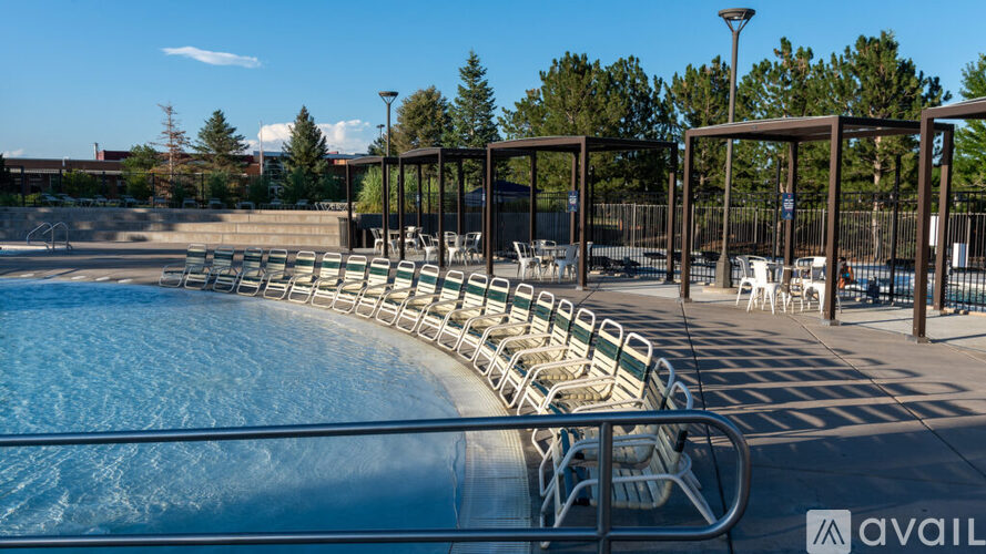 A pool with a metal railing and chairs around it.