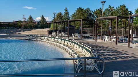 A pool with a metal railing and chairs around it.