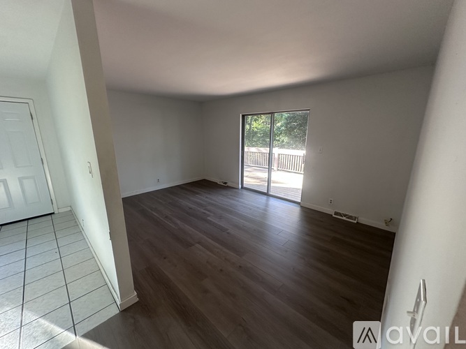 A room with wooden flooring and a sliding glass door leading outside.