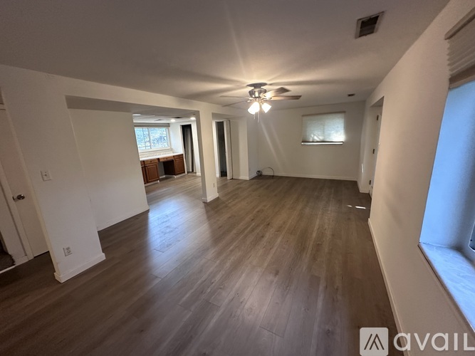 A spacious room with wooden flooring and a ceiling fan.
