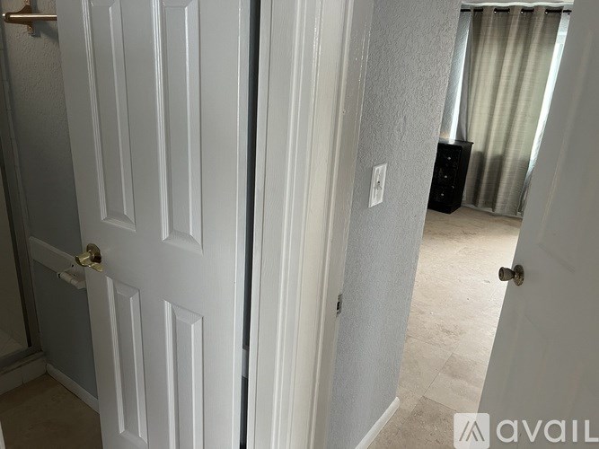A white door with a gold handle is open to a room with a carpeted floor.
