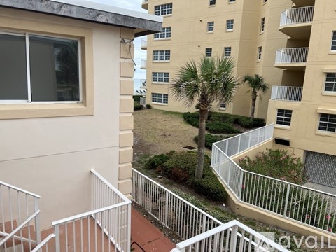A view from a balcony looking down at a palm tree and other buildings.