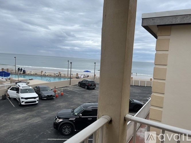 A parking lot with cars and a beach in the background.