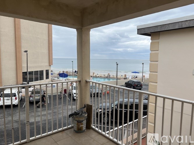 A balcony with a railing overlooking a parking lot and beach.