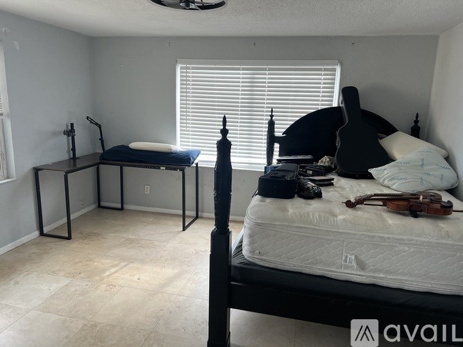 A room with a bed, a chair, and a violin on the bed.