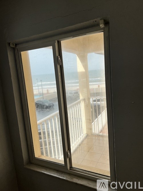 A window with a view of a beach and a balcony.