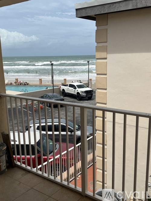A car is parked on a balcony overlooking the beach.