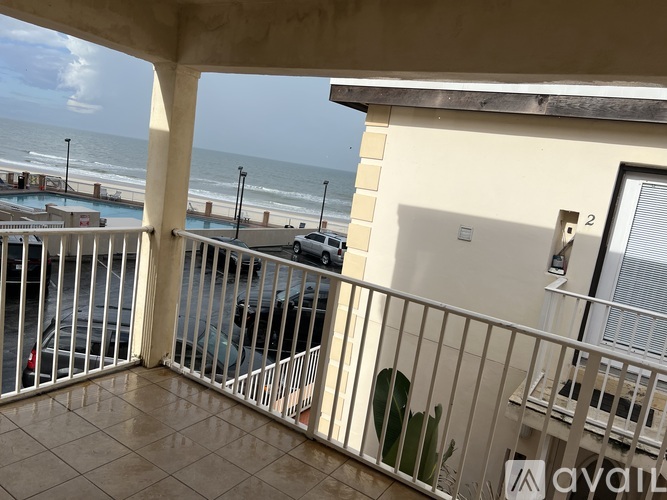 A balcony with a view of the beach and a pool.