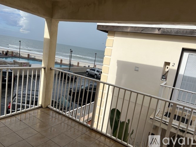 A balcony with a view of the beach and a pool.