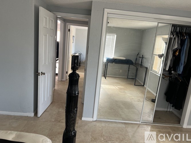 A bedroom with a bed and a wardrobe is visible through a glass door.