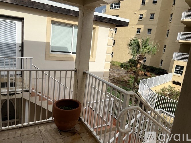 A balcony with a white railing and a large terracotta pot.