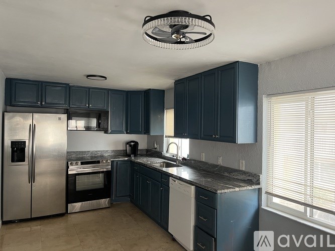 A kitchen with dark blue cabinets and stainless steel appliances.
