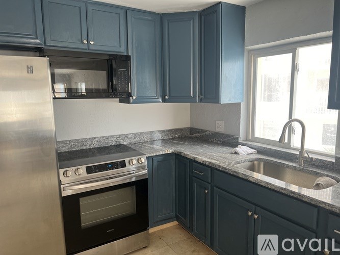 A kitchen with dark blue cabinets and stainless steel appliances.
