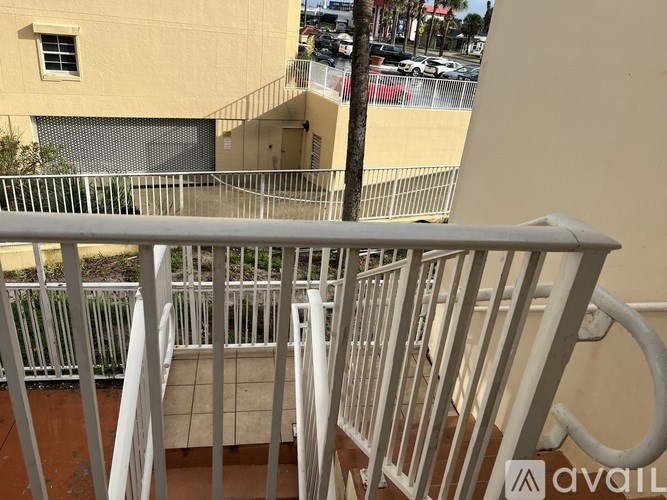 A balcony with a metal railing and a view of a parking lot.