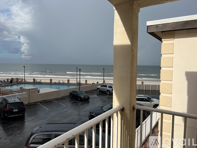 A balcony view of a parking lot with cars and a pool.