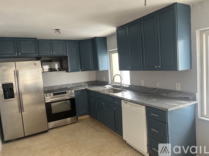 A kitchen with dark blue cabinets and stainless steel appliances.