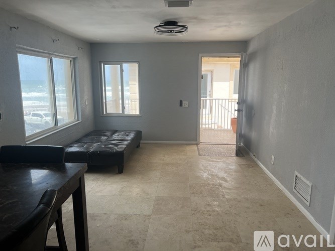 A room with a table and chairs and a window overlooking the beach.