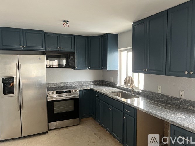 A kitchen with dark blue cabinets and a stainless steel refrigerator.